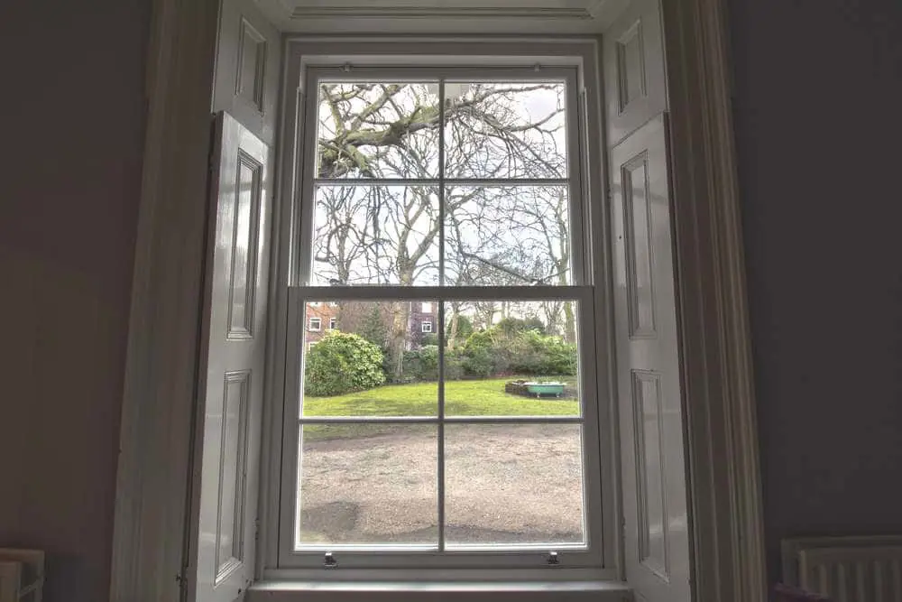 Internal shot of UPVC sash window with original wooden shutters.