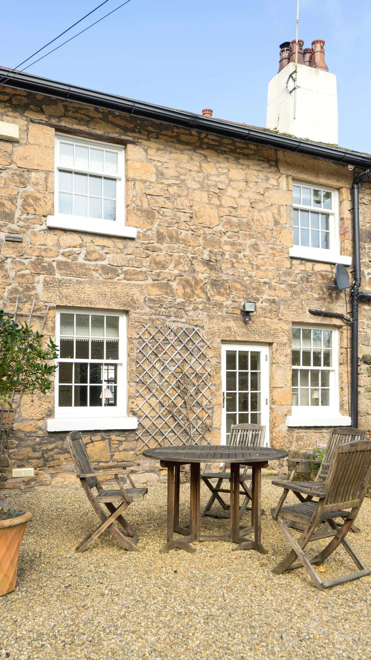 Vertical image showing outdoor dining area of property with newly installed windows and doors.