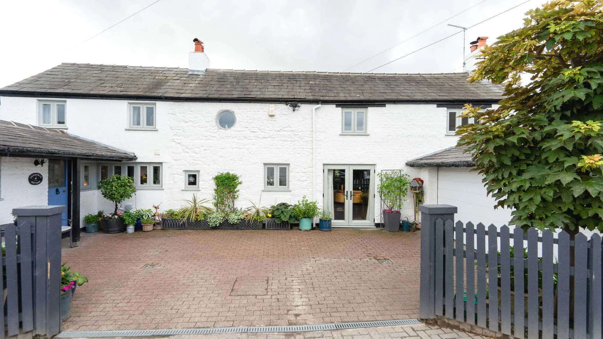 Front façade of this full house window installation on The Wirral featuring white render and agate grey windows.